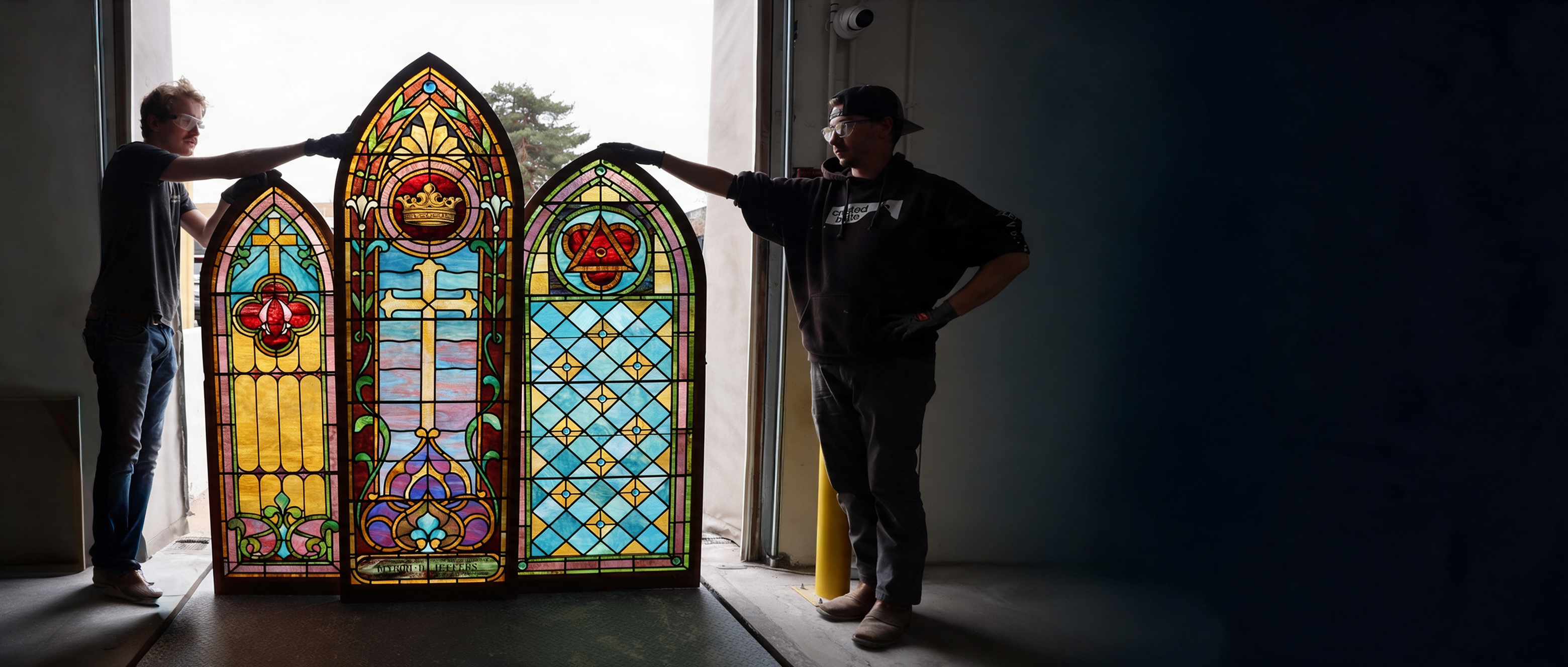 Stained glass artisans working on a leaded glass panel in the studio
